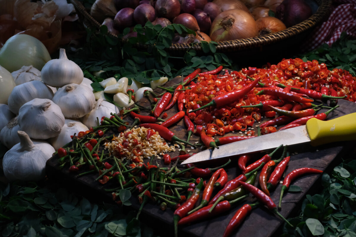 chili on a chopping board, onions and garlic on the side